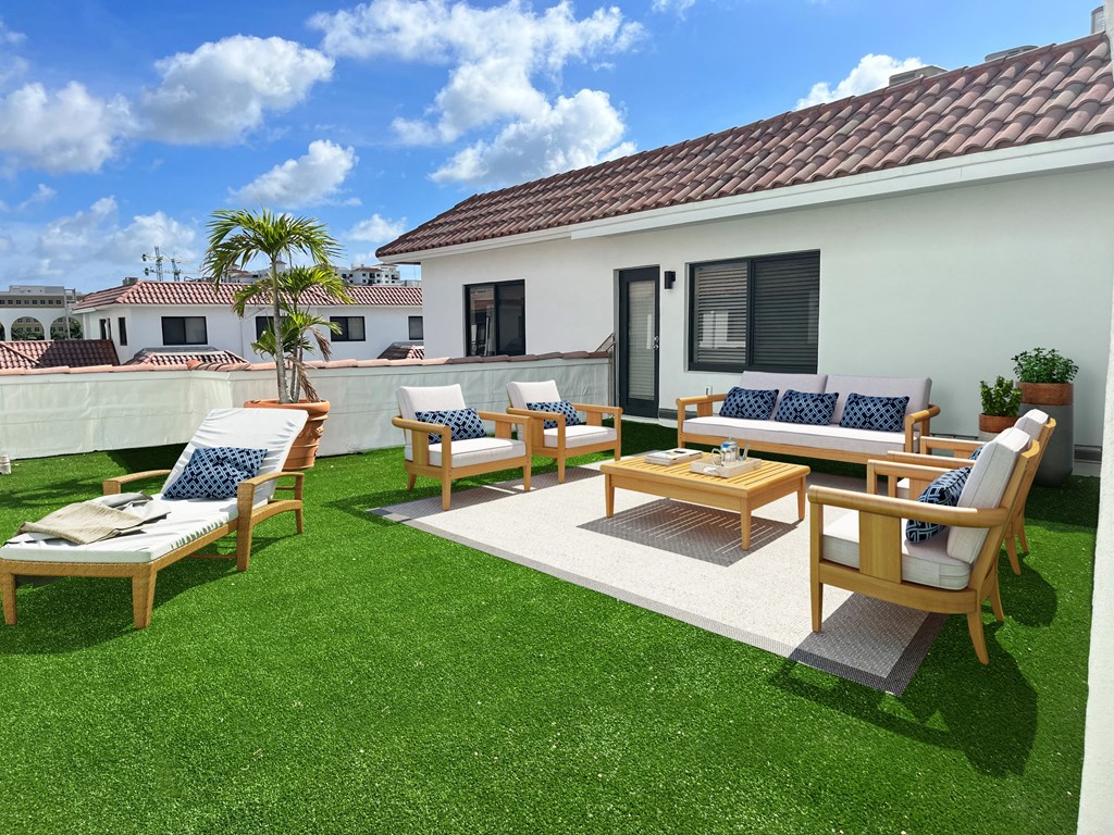 a backyard patio with wooden furniture and a white house